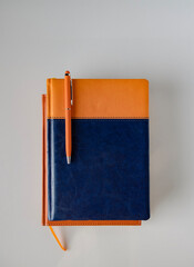 There is an orange pen on a stack of diaries, there is space for text, selective focus.