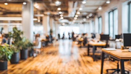 Blurred view of modern open-plan office with desks, plants, and natural light