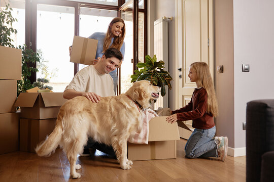 Family unpacking belongings with dog after moving into new home