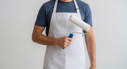 Man in a white apron holding a paint roller. Renovation process concept. Painter service, diy home improvement, and repair workshop.
