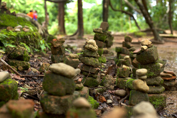 A Zen symbol in the form of a stone pyramid stands majestically in the middle of a river amidst a lush natural forest.