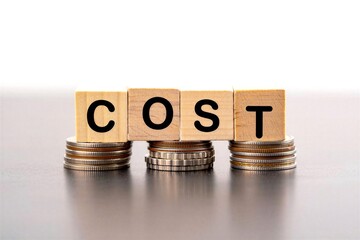 Wooden blocks spelling out cost on stacks of coins representing financial expenses and budget management concept