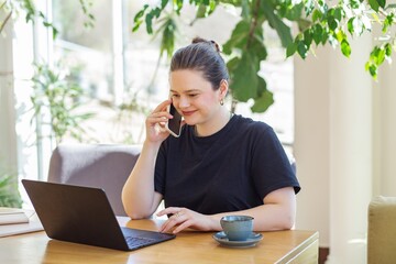 Woman working on laptop and phone in cafe