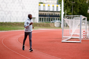 Obraz premium Young man jogging on outdoor stadium track