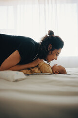 Tender moment of mother interacting with baby on bed