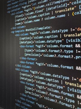 Close-up shot of a computer monitor displaying lines of source code in a dark-themed editor. The image captures colorful syntax text, structured code layout, and visible screen texture, representing m