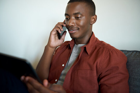 Young African man talking on his phone while working from home