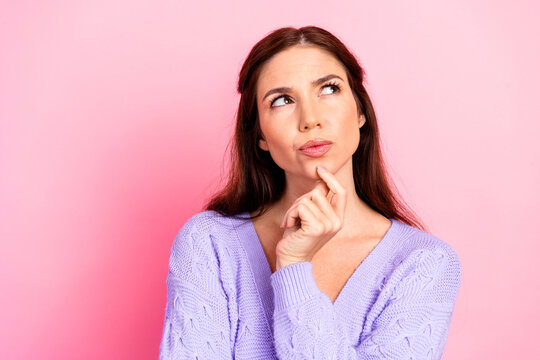 Contemplative young woman in a lavender sweater thoughtful pose against pink background