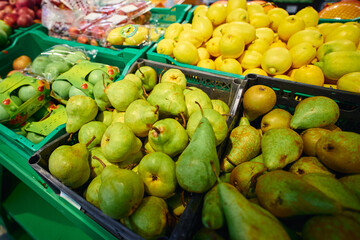 Bright green and yellow pears are arranged in bins at a local market