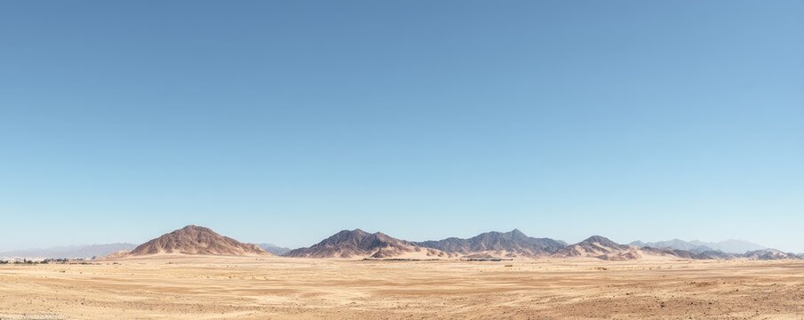 Wide empty desert landscape with vast sandy plain and distant rocky mountains under a clear blue sky, ideal for minimal natural backgrounds and environmental openness concepts