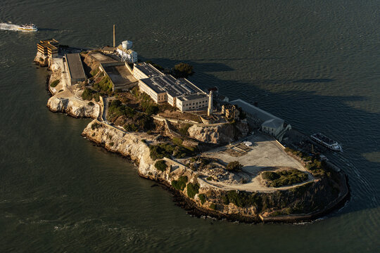 Aerial view of Alcatraz Island, a somber fortress rising from the shimmering bay waters, its weathered walls echoing tales of isolation and resilience, San Francisco, California, United States.