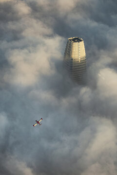 Aerial view of a small plane soars past the misty Salesforce Tower, an iconic landmark piercing through the dense fog, San Francisco, California, United States.