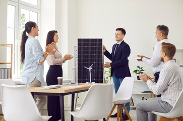 Businessman conducting a presentation on solar panels or renewable energy sources for a group of colleagues or clients during a meeting in the office. Discussing importance of alternative power.