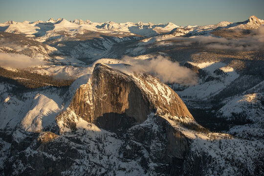 Aerial view of Half Dome's granite face kissed by the sun, amidst a snowy embrace, Sierra Nevada, California, United States.