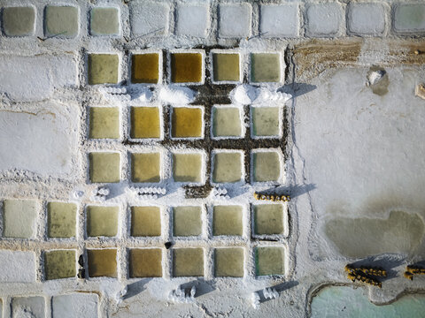 Aerial view of geometric salt ponds, their pastel hues contrasting with the stark white salt crystals, creating a surreal landscape, Daghmar, Oman