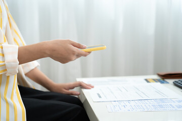 woman use phone scan barcode or QR codes to pay credit card bill after receiving document invoice. payment, receive, paying electricity, digital payments, technology, scanning, financial transactions