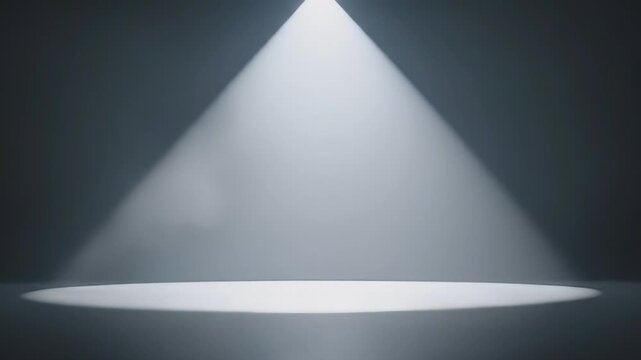 A dramatic overhead spotlight illuminates a perfectly circular area on a clean, empty stage or studio floor, creating a dynamic visual effect. Subtle atmospheric haze and dust particles are visible wi