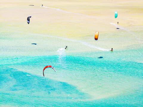 Aerial view of kitesurfers dance across the turquoise waters, their colorful kites painting the sky above the sandy shores, Parco natural de Jandia, Costa Calma, Fuerteventura, Canary Islands, Spain.