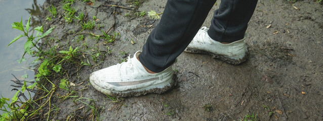 Man with a shoes stands on the dirty ground.
