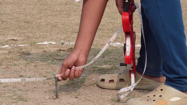 Person measuring land in square feet with tape for sale