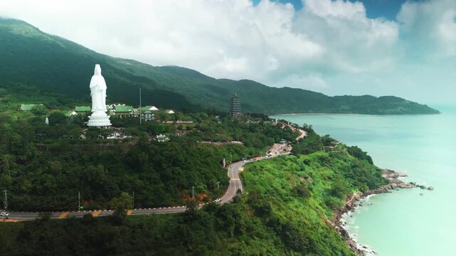Lady buddha statue overseeing the calm turquoise ocean and surrounding mountains, presenting a spiritual landscape of cultural heritage and natural beauty in da nang, vietnam