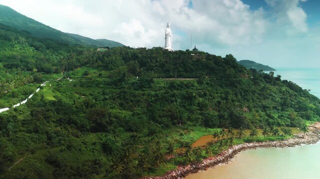 Linh ung pagoda complex featuring the standing buddha statue of quan am, goddess of mercy, overlooking the calm ocean and lush green mountains of son tra peninsula in da nang, vietnam