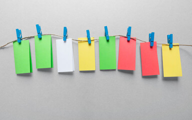 Colored cards hanging with blue clothespins, gray background