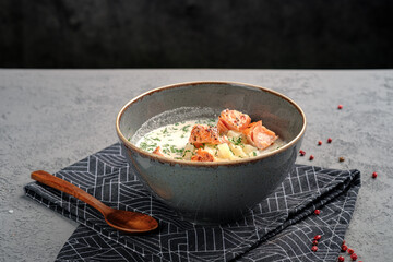 Creamy Finnish salmon soup (lohikeitto) with tender grilled salmon chunks, diced potatoes and fresh dill garnish in rustic bowl. Traditional Nordic fish chowder