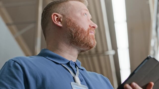 Low angle shot of bearded male shop assistant working on black table which holding in hands