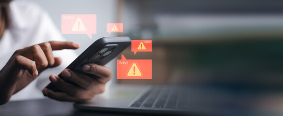 Closeup hand holding smartphone with red warning alert icons. Concept of cyber security, spam message, phishing scam, system error and digital data protection awareness.