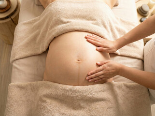 Side View Close Up Therapist Hands Massaging Pregnant Woman Belly with Oil in Spa