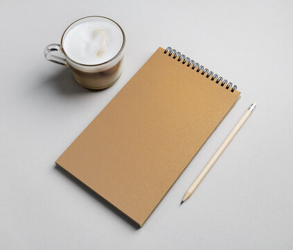 Blank sketchbook, coffee cup and pencil on gray paper surface.
