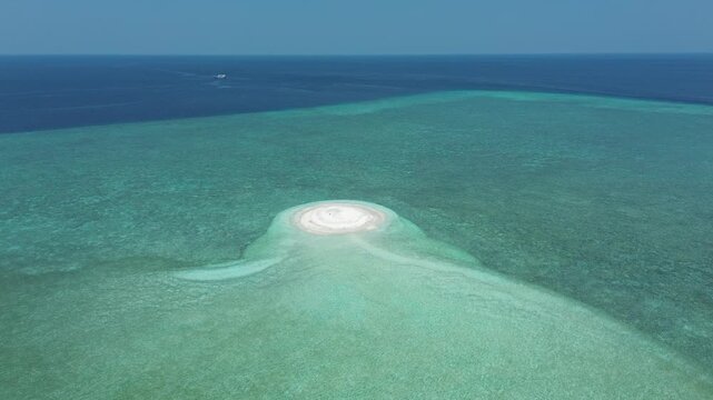 Drone footage reveals expansive coral reef flats and white sandbars under shallow tropical water in Banda Sea.