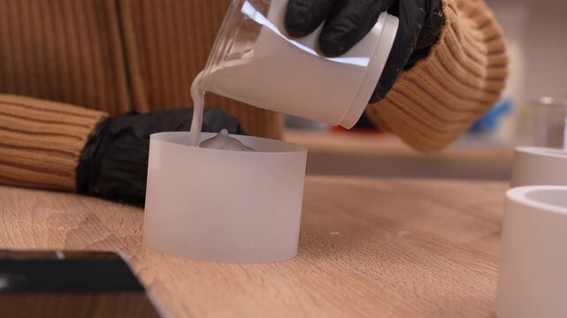 Pouring liquid gypsum plaster into silicone mold for candlestick making