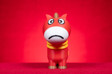 a toy horse with crying face on red