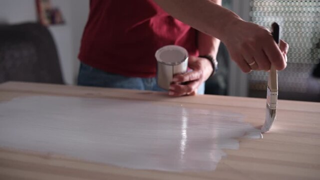 Woman Painting A Wooden Surface Of A Table Using A Brush