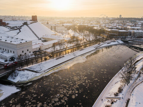 Aerial view of ice floes dance on the river Neris, reflecting the golden light near Gediminas' Tower and the snow-dusted cityscape, Vilnius, Vilnius County, Lithuania.