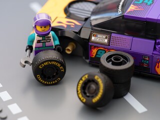 Obraz premium Tambov, Russian Federation - January 17, 2026 Lego driver minifigure changing wheel of a his Lego NASCAR Next Gen Chevrolet Camaro ZL car. LEGO Speed Champions.