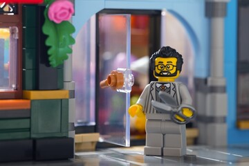 Obraz premium Tambov, Russian Federation - June 28, 2025 Lego barber minifigure with scissors standing near the entrance of his salon outdoors