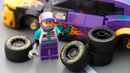 Naklejka premium Tambov, Russian Federation - January 17, 2026 Lego driver minifigure with wrench ready to chang wheels on his Lego NASCAR Next Gen Chevrolet Camaro ZL car. LEGO Speed Champions.