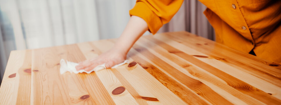 Cleaning service worker wiping wood table surface in home. Professional maintenance furniture domestic housework interior concept