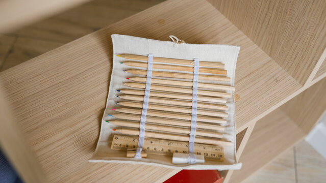 Natural wooden colored pencils and ruler in fabric pouch on wooden shelf