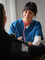 Native American nurse with scrubs and stethoscope takes blood pressure 