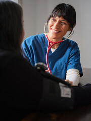 Native American nurse with scrubs and stethoscope smiles at elderly patient