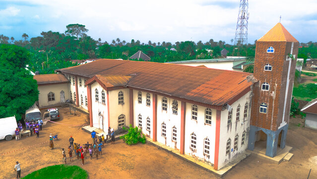 Aerial view of the church with a brick tower and red roof stands out against the sandy ground and lush greenery, Oduoha-Emuoha, Rivers, Nigeria.