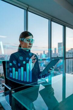 Woman monitoring real time data visualizations on holographic interface while using tablet