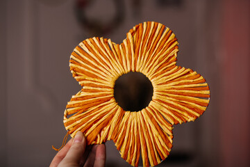 Decorative yellow orange straw flower held in hand against neutral background