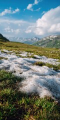 Fototapeta premium Snow melting on alpine meadow in summer with blue sky and clouds