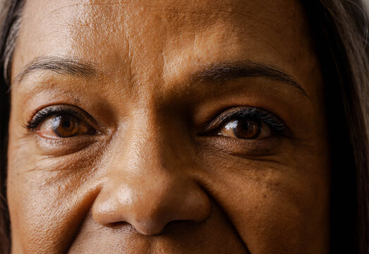 Mature woman looking directly at camera in studio, showing pores, fine lines, eyeliner