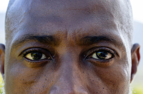 Mature African American man showing close facial texture and eye corneal reflections outdoors